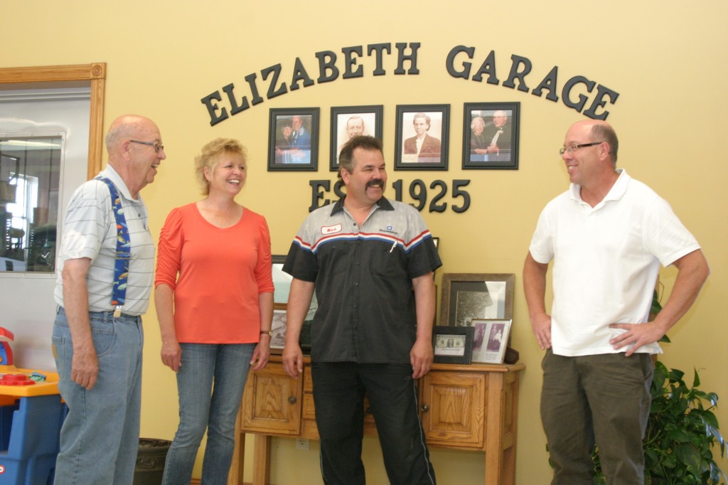 Jack Graves (left) and children, Jennifer, Jeff and Jay laugh together in the lobby of the Elizabeth Garage. A history of the establishment is on display behind them.