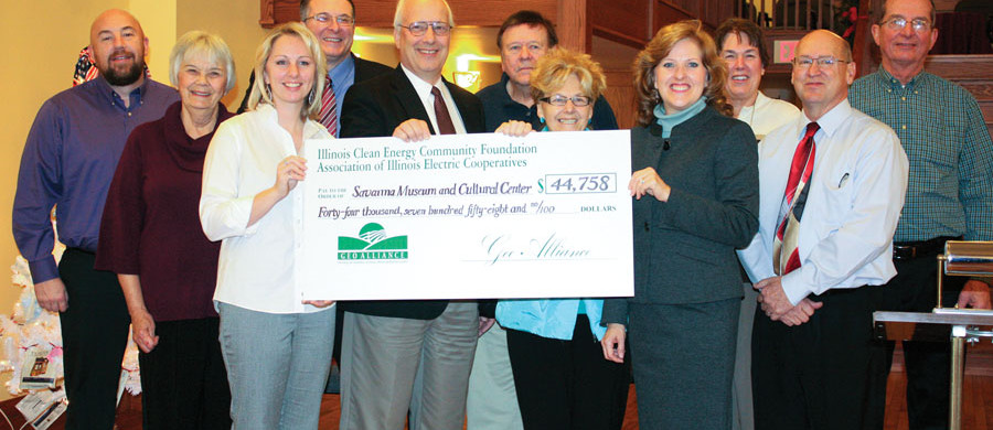 Shown at the Savanna Museum and Cultural Center GeoAlliance geothermal check presentation from left, front row, are: Heidi Weber, Jo-Carroll Energy Manager of Member Relations and Marketing; John LeComte, Savanna Historical Society (SHS) Board Member; Jeannine Mills, SHS Board Member; Nancy McDonald, Association of Illinois Electric Cooperatives Marketing Administrator; and Larry Stebbins, Mayor of Savanna. Pictured from left, back row are: John Scott, Jo-Carroll Energy, Inc. Energy Advisor; Jean Jones, SHS Treasurer; State Senator Mike Jacobs; Gene Wright, SHS Board Member; Carol Wright, SHS Board Member; and Keith Brown, SHS Vice-President.
