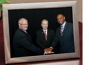 Phil Carson standing with two other NRECA board members. 