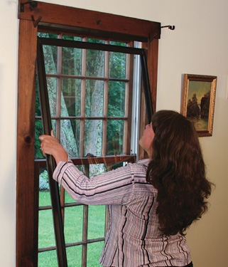 Woman installing a storm window in her house