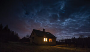 Landscape with house at night under cloudy sky. Spooky landscape with house in night.