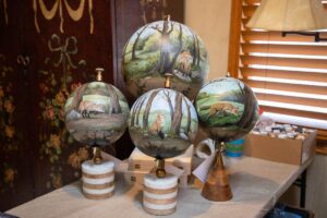 One large globe and three small globes all painted with scenes of a fox in a forest.