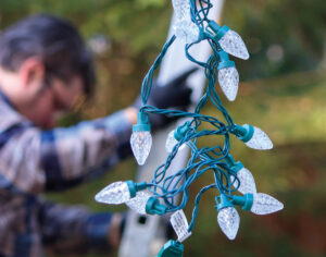 Man hanging Christmas lights during winter from a ladder