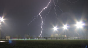 Lightning strikes a sports field on a rainy night
