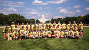 A large group of high school students pose in their yellow Youth Tour shirts in DC