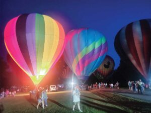 Hot air balloons are colorful while lit up at dusk