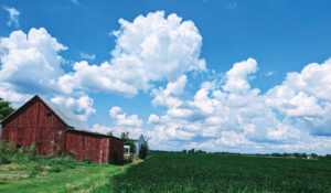 A red barn sits at the edge of a green field