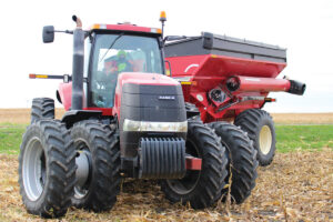 A woman drives a red tractor during harvest time
