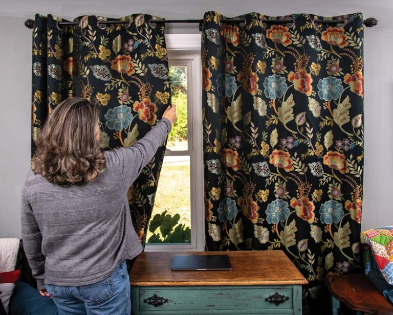 A woman reaches up to close curtains