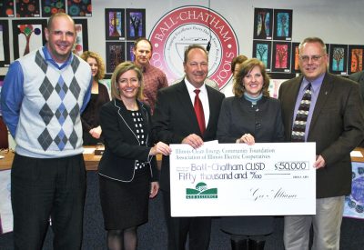 Presenting a $50,000 grant check at the Ball-Chatham School Board meeting, from right are David Stuva, President/CEO of Rural Electric Convenience Cooperative, and Nancy McDonald, Marketing Administrator for Association of Illinois Electric Cooperatives. Accepting the grant are Board President Rick Petermeyer, Superintendent Carrie Hruby, and Nate Fretz, Chief School Business Official.