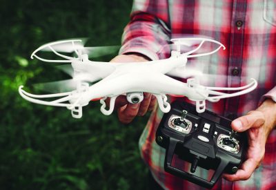 Operator holding remote control and quadrocopter. Unmanned aerial copter starting in forest. Aeromodelling, hobby, leisure concept