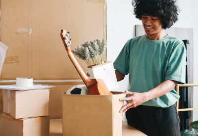 Young Asian man putting stuff into carton box preparing moving t