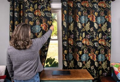 A woman reaches up to close curtains