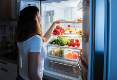 Woman looking into open refrigerator