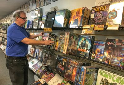 Scott Thorne, owner of Castle Perilous Games and Books in Carbondale, straightens board games on his store’s shelves.  Photo by Les O’Dell