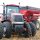 A woman drives a red tractor during harvest time