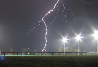 Lightning strikes a sports field on a rainy night
