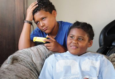 Two children are playing a video game. The boy appears to have lost and the girl is smiling while holding a wireless controller