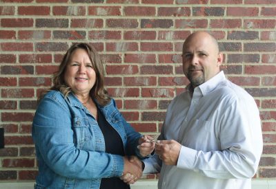 Tamara Phillips, retiring Norris Electric Cooperative general manager, passes the keys to the co-op to her successor Luke Johnson, former CEO of Tri-County Electric Cooperative.