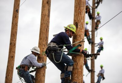 Drayton Davis (right) competes in and wins the 40-foot transition climbing challenge at the Lineman’s Safety Rodeo. Davis, a Rural Electric Convenience Cooperative lineworker, also earned best individual lineman overall.