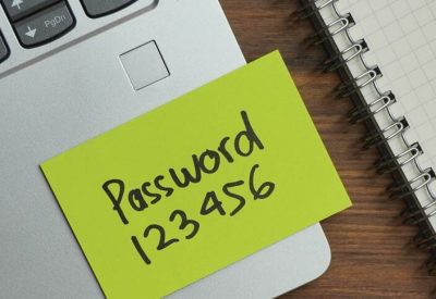Sticky note with the word "password 123456" on a laptop keyboard