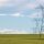 Power lines in a farm field on a sunny day with clouds